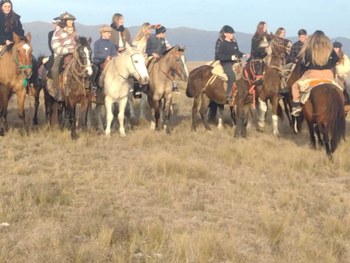 Grupo grande a caballo reunido al caer la tarde